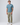 Blue t-shirt paired with light trousers and white trainers in studio.