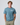 Blue short sleeve t-shirt with logo patch styled with beige trousers.