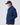 Side view of a model wearing a collared button-up jacket with hands in the front pockets and a baseball cap.