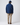 Back view of a model wearing a collared jacket with straight-leg trousers and casual shoes.