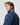 Close-up of man in navy jacket with high collar, sleeve crest, and grey reflective collar detail.