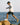 Model wearing white Henri-Lloyd Dynamic Jacket stepping across rocks by the sea – active outdoor lifestyle scene.