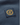 Embroidered crest patch with HL initials and crown in gold thread on navy fabric sleeve.
