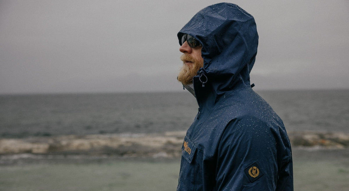 Person wearing waterproof Jacket with hood up in the rain by the sea.