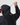 Back view of model wearing the Men's Dynamic Jacket in black, adjusting hood with drawcord for fit in wet weather.