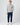 Light grey cable knit sweater paired with navy trousers and trainers.