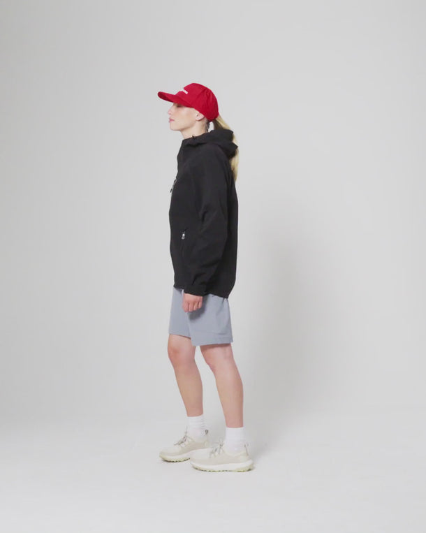 Model wearing Henri-Lloyd jacket side profile, paired with red cap and shorts.