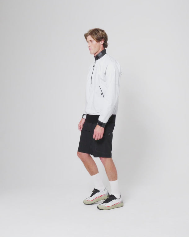 Model walking in the Dynamic Smock – Black paired with black shorts and trainers against a plain background.
